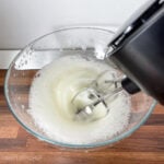 Beating egg whites with electric mixer before adding them to pancake batter.