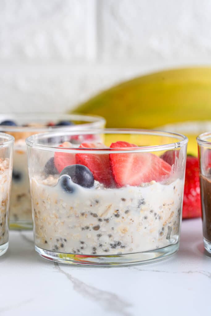 Overnight oats in a glass jar topped with fresh sliced strawberries and fresh blueberries.