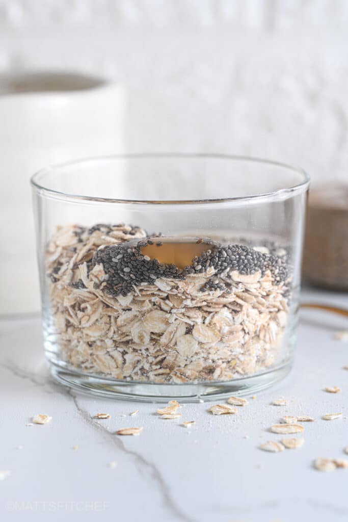 Old fashioned rolled oats, chia seeds and maple syrup in a glass, ready to add milk