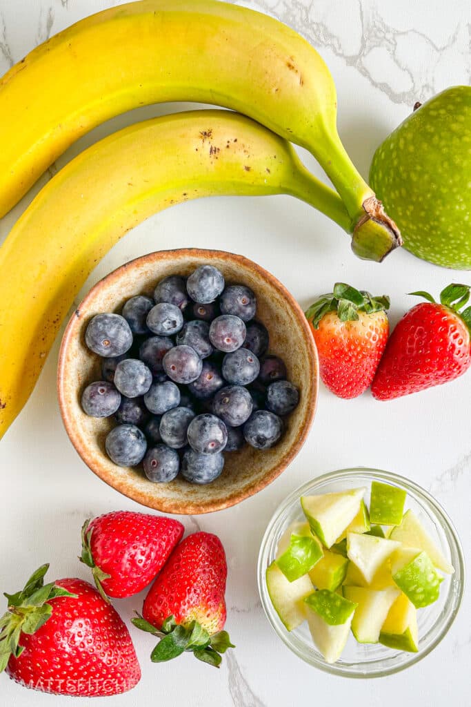 Fruit toppings for oatmeal &ndash; sweet bananas, vibrant strawberries, juicy blueberries and green apple diced in small pieces