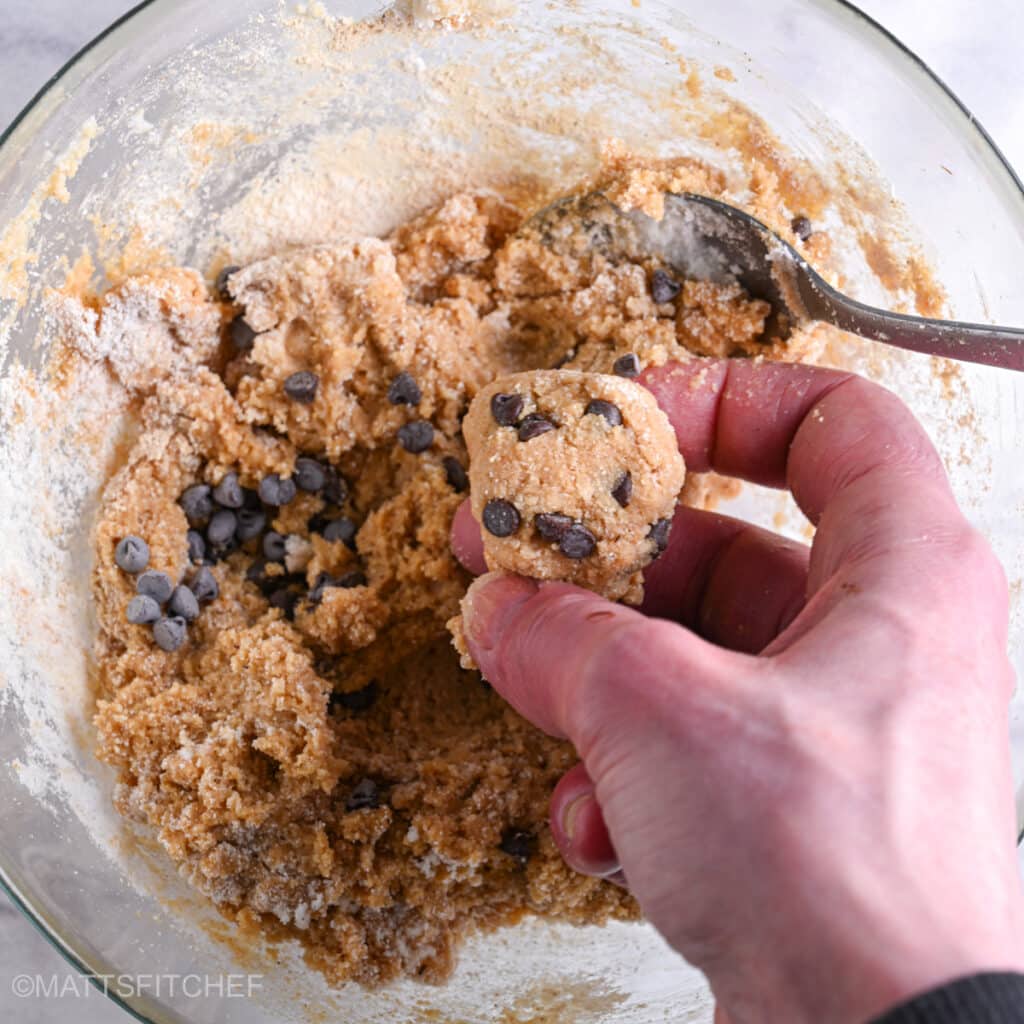 Forming by hand protein balls from cookie dough made with dark chocolate chips.