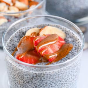 Close-up of high protein chia pudding, topped with sliced strawberries, bananas, and almond butter. Perfect as a low carb and dairy-free snack or dessert.