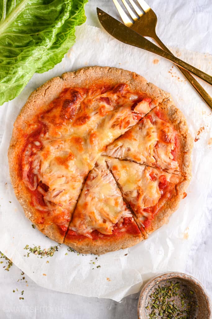 Greek yogurt pizza base topped with shredded chicken cut into 3 slices, after baking ready to eat