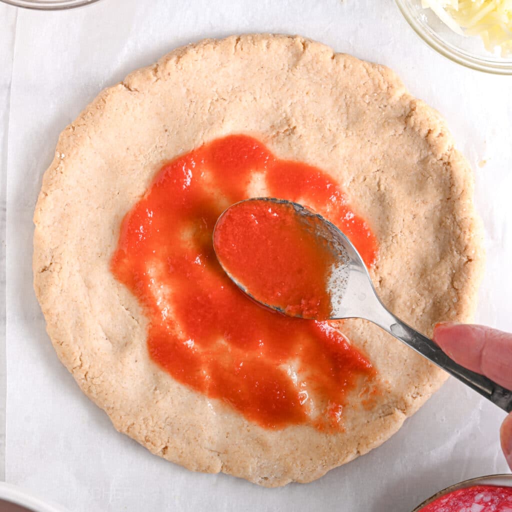 Spreading tomato sauce on top of Greek yogurt protein crust