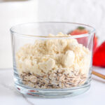 Rolled oats and protein powder in a glass, while preparing protein overnight oatmeal