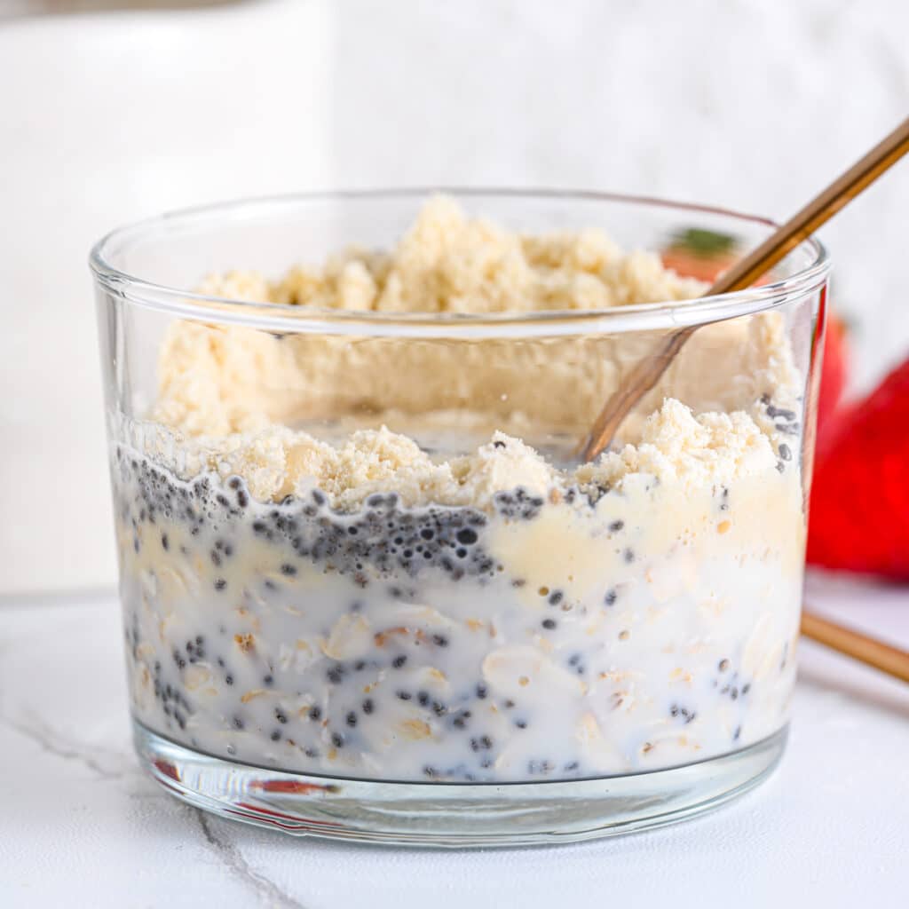 Mixing protein powder and rolled oats with a golden spoon, after adding milk – before refrigerating to soak