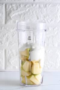 Adding Greek yogurt to diced apple in a high speed blender, before adding cocoa powder and mixing.
