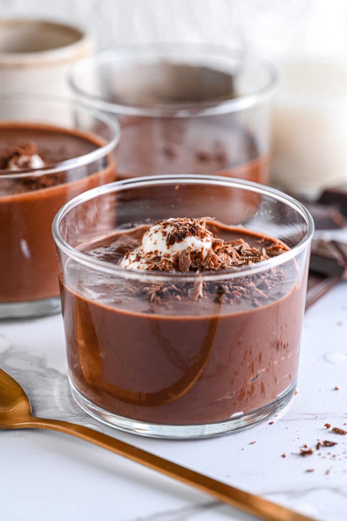 Sugar-free chocolate pudding in dessert glasses, topped with Greek yogurt and shaves of dark chocolate.