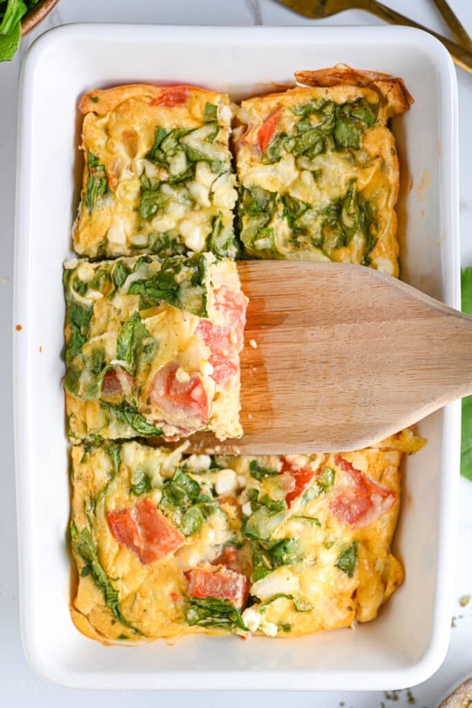 Sliced of Baked Cottage Cheese Eggs Being Served With A Wooden Spatula.