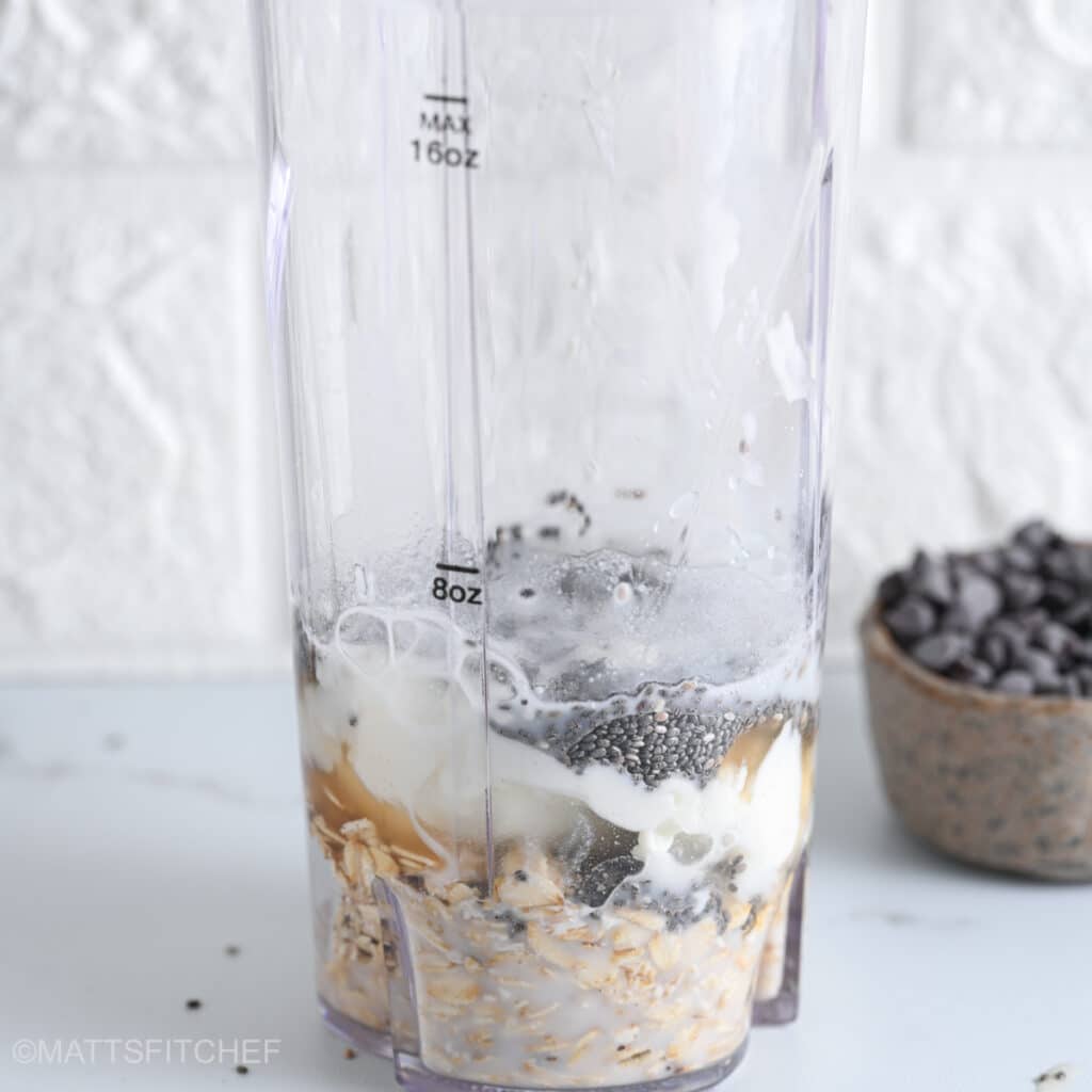 Milk being added to blended overnight oats ingredients in a blender