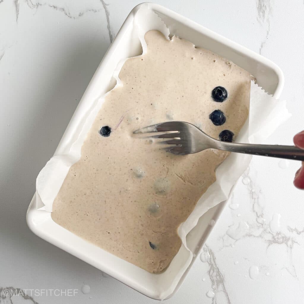 Stirring blueberries inside batter with fork