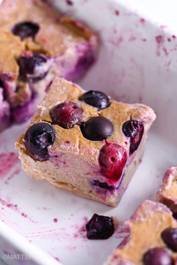 Close up of sliced cottage cheese blueberry bake in baking pan, with juicy blueberries