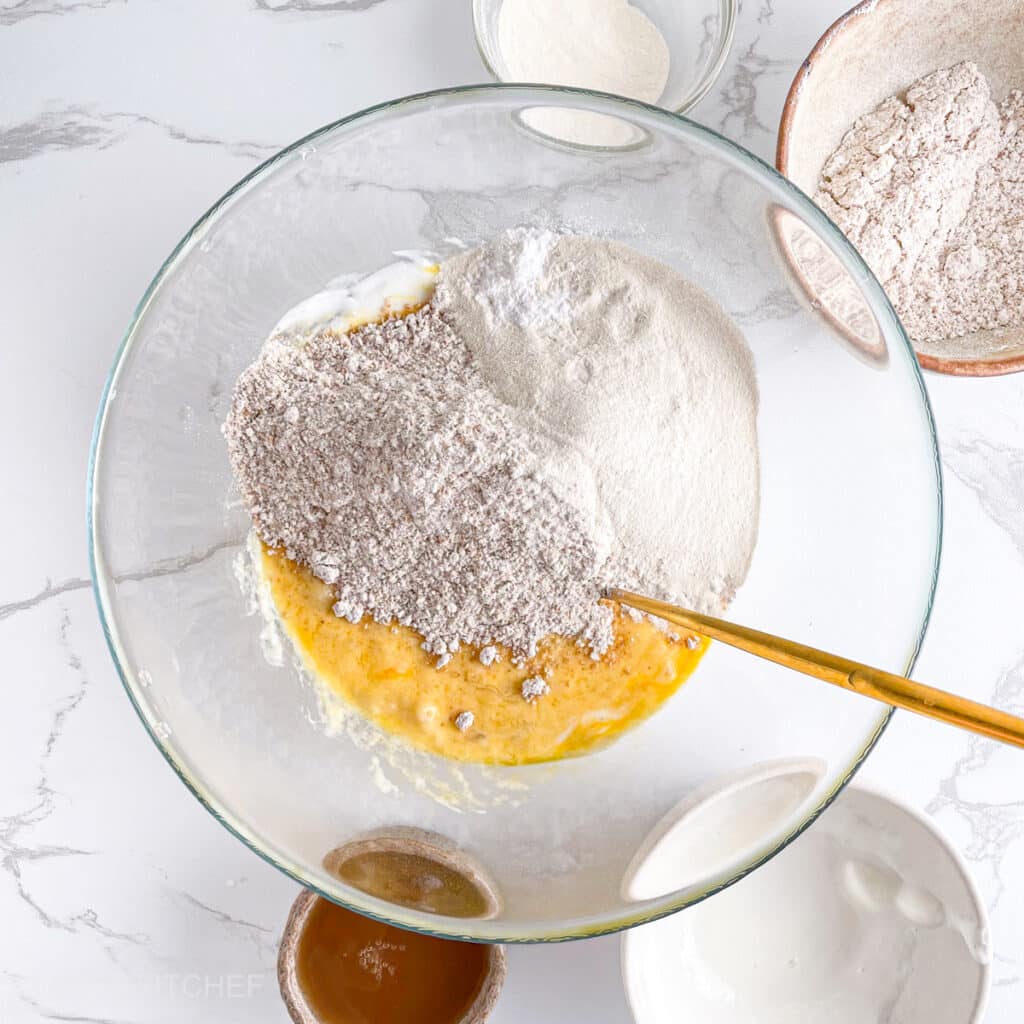 Adding gluten-free oat flour and almond flour or protein powder to wet mixture, ready to stir until smooth.