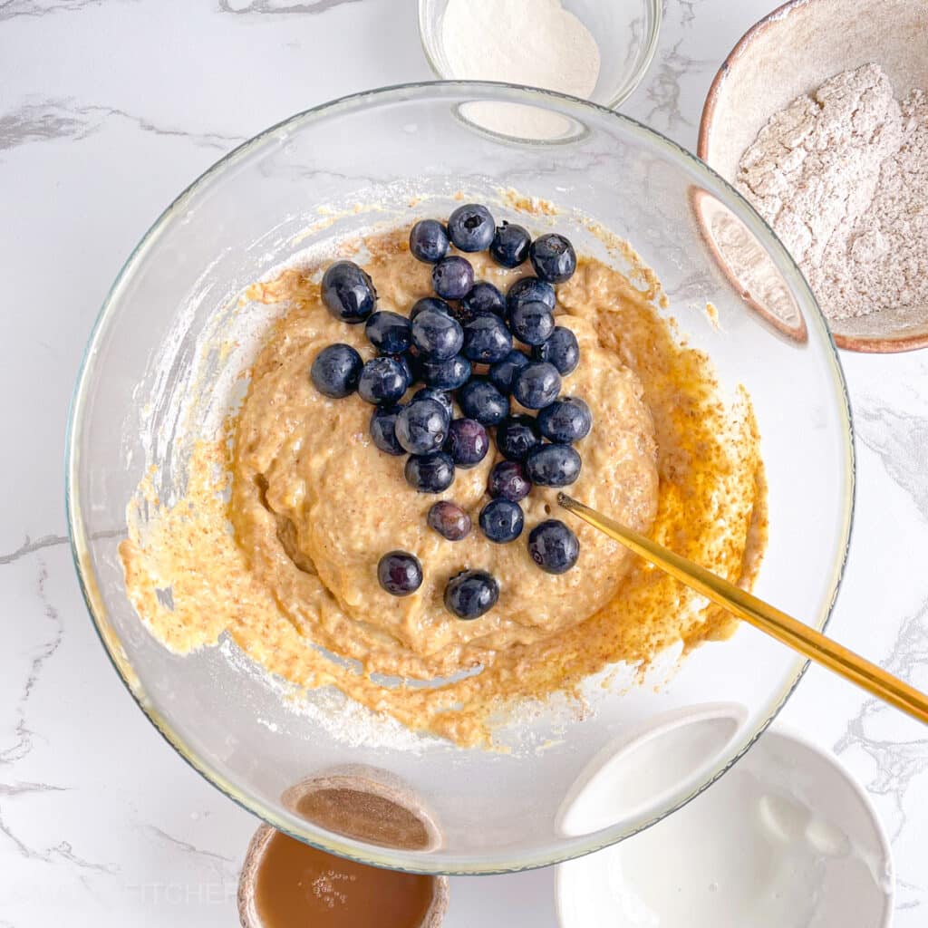 Adding fresh blueberries to cottage cheese muffin batter, ready to stir and bake