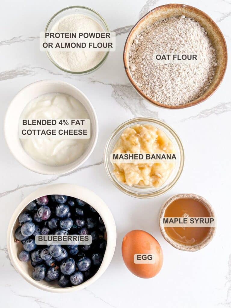 Cottage Cheese Blueberry Muffins Ingredients - Oat flour, protein powder or almond flour, blended cottage cheese, mashed banana, maple syrup, egg, fresh blueberries