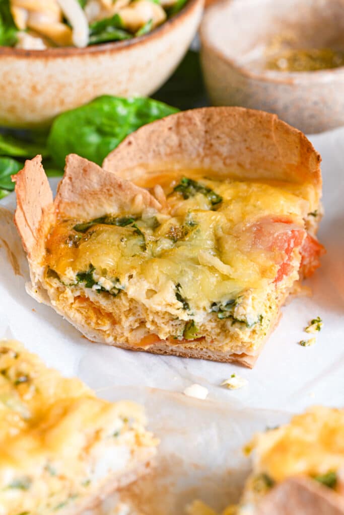 Close-up of a baked tortilla quiche slice, made with creamy cottage cheese, chopped spinach and diced tomatoes.
