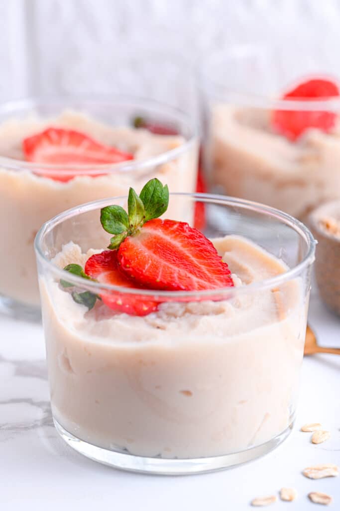 Blended overnight oats in glass jars, topped with strawberries
