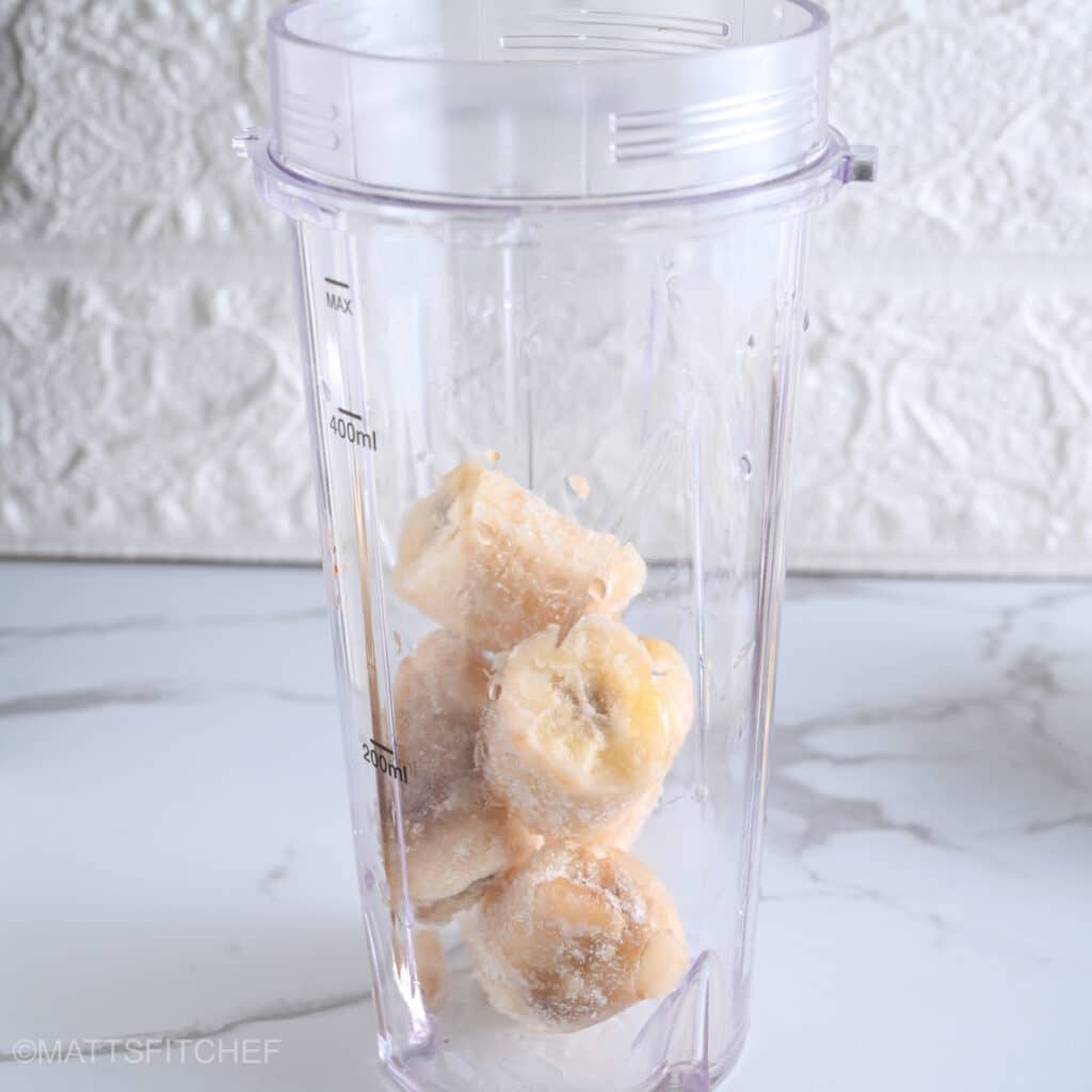 Frozen bananas cut into chunks in a blender, ready to combine with the other ice cream ingredients