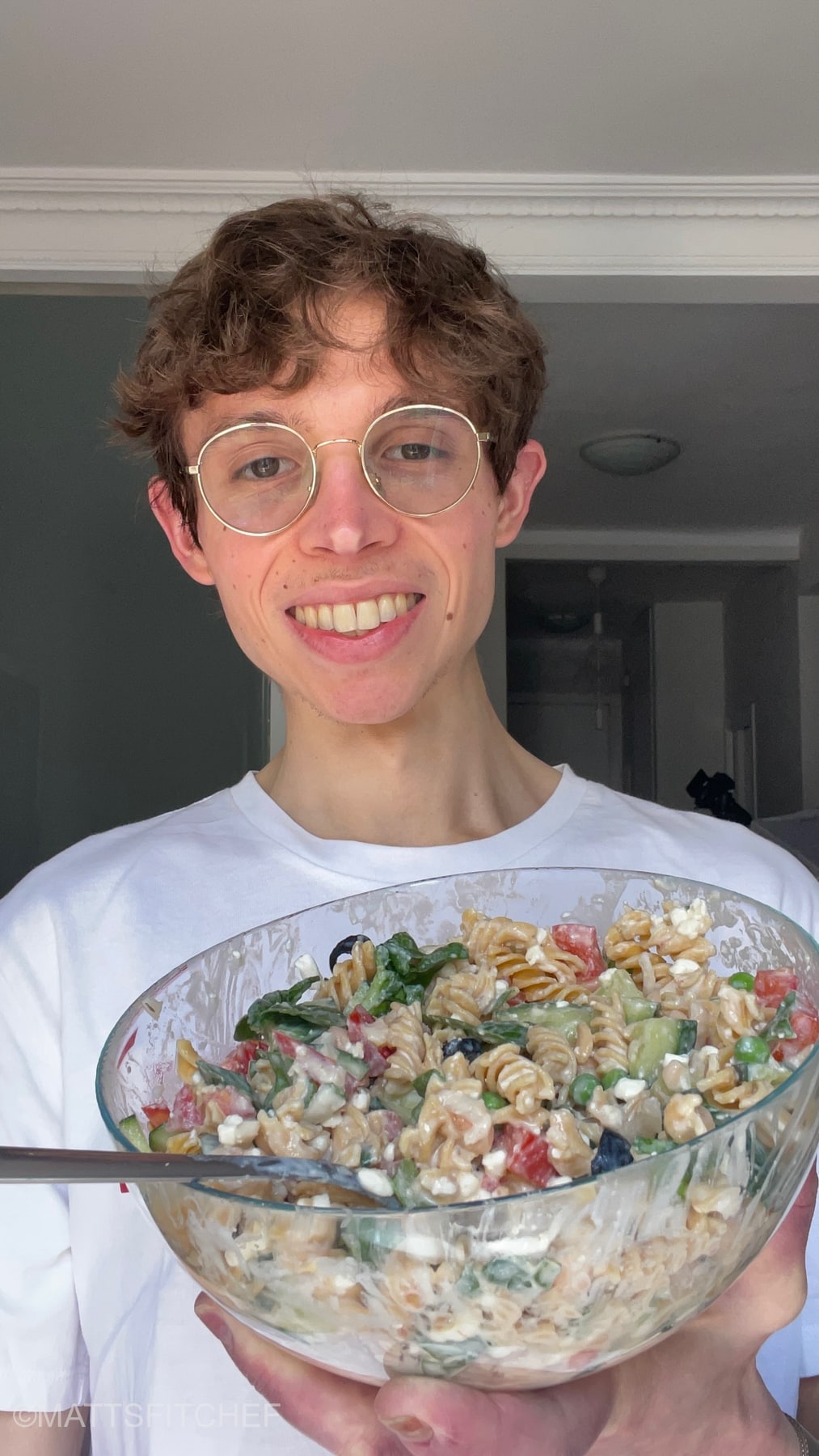 Matteo, MattsfitChef, holding in the hand a large bowl of high protein vegetarian salad. The fitness chef shows a smiling face, highlighting his liking for the dish.
