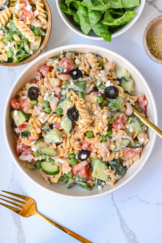 High Protein Pasta Salad in a plate, shown from the top. This cold summer dish is loaded with summer vegetables, protein-packed cottage cheese and beans, and a creamy dressing that is low calorie and high in vegetarian protein