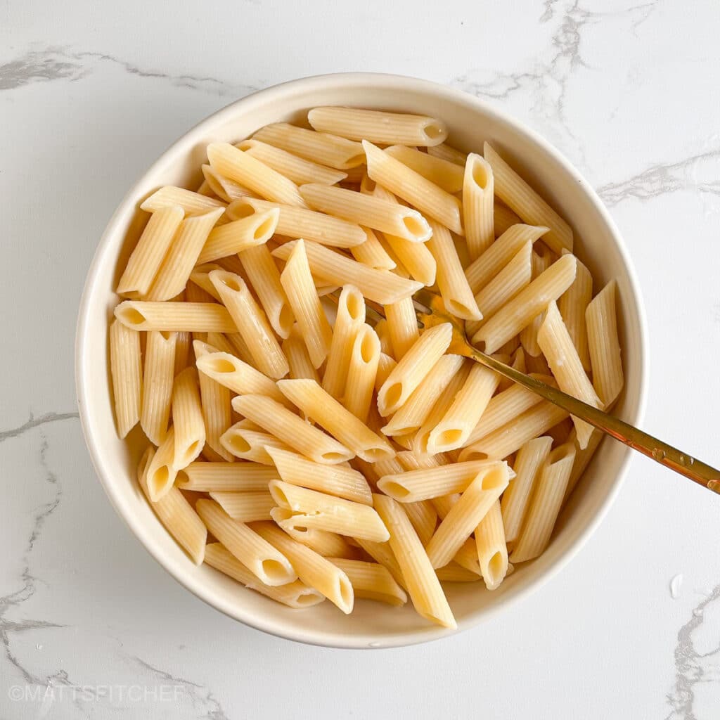 Cooked penne in a bowl after cooking, ready to mix with the other low calorie ingredients.