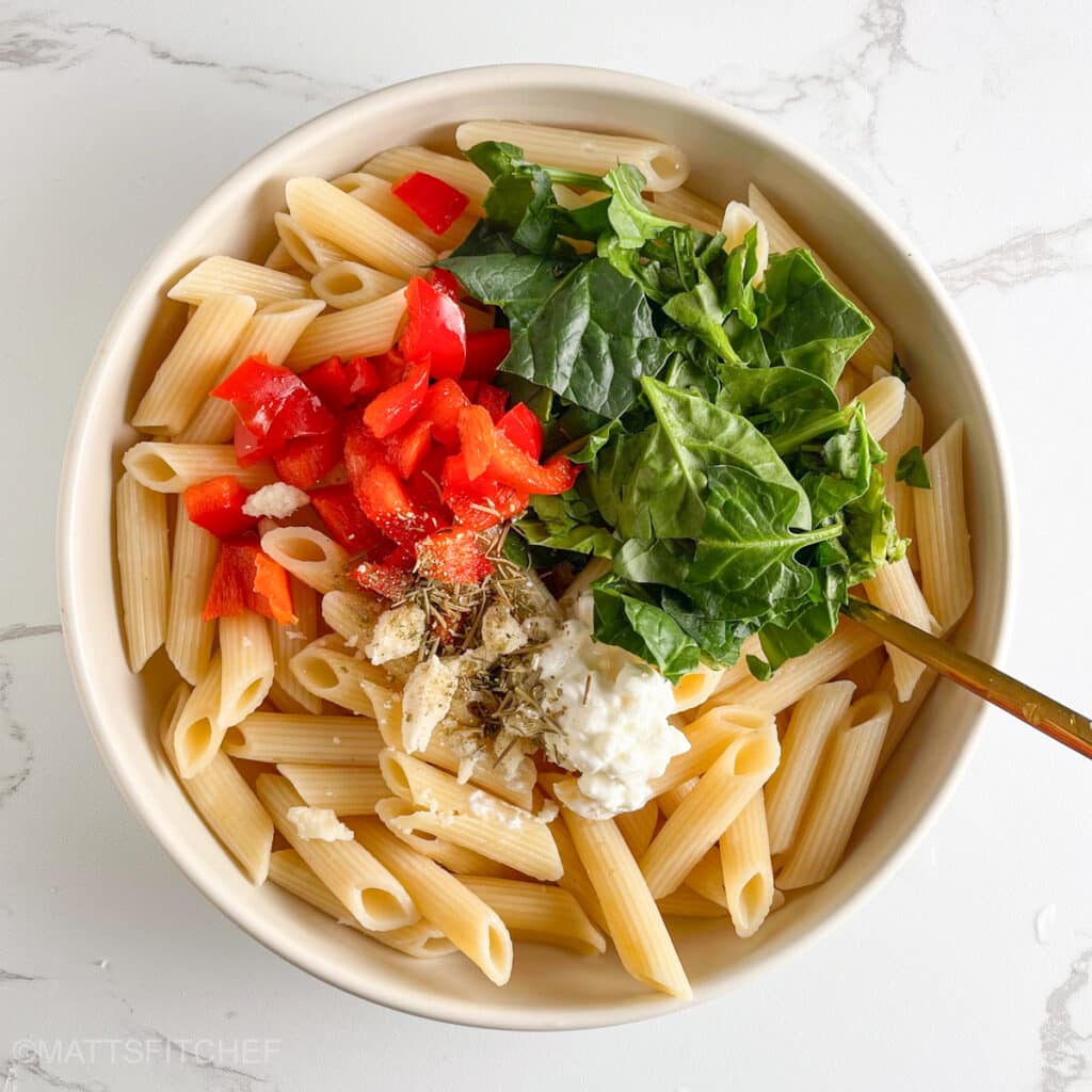 All components of the weight loss pasta salad in a bowl, ready to toss with a fork.