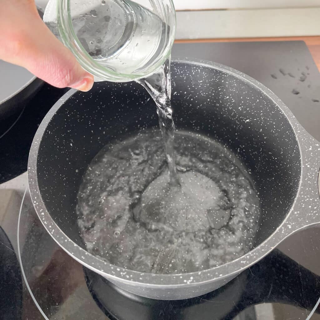 Pouring water into a pot to boil, as the first step of making savory oatmeal for a quick breakfast or dinner