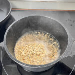 Rolled oats added to a pot of boiling water, ready to simmer for a savory porridge