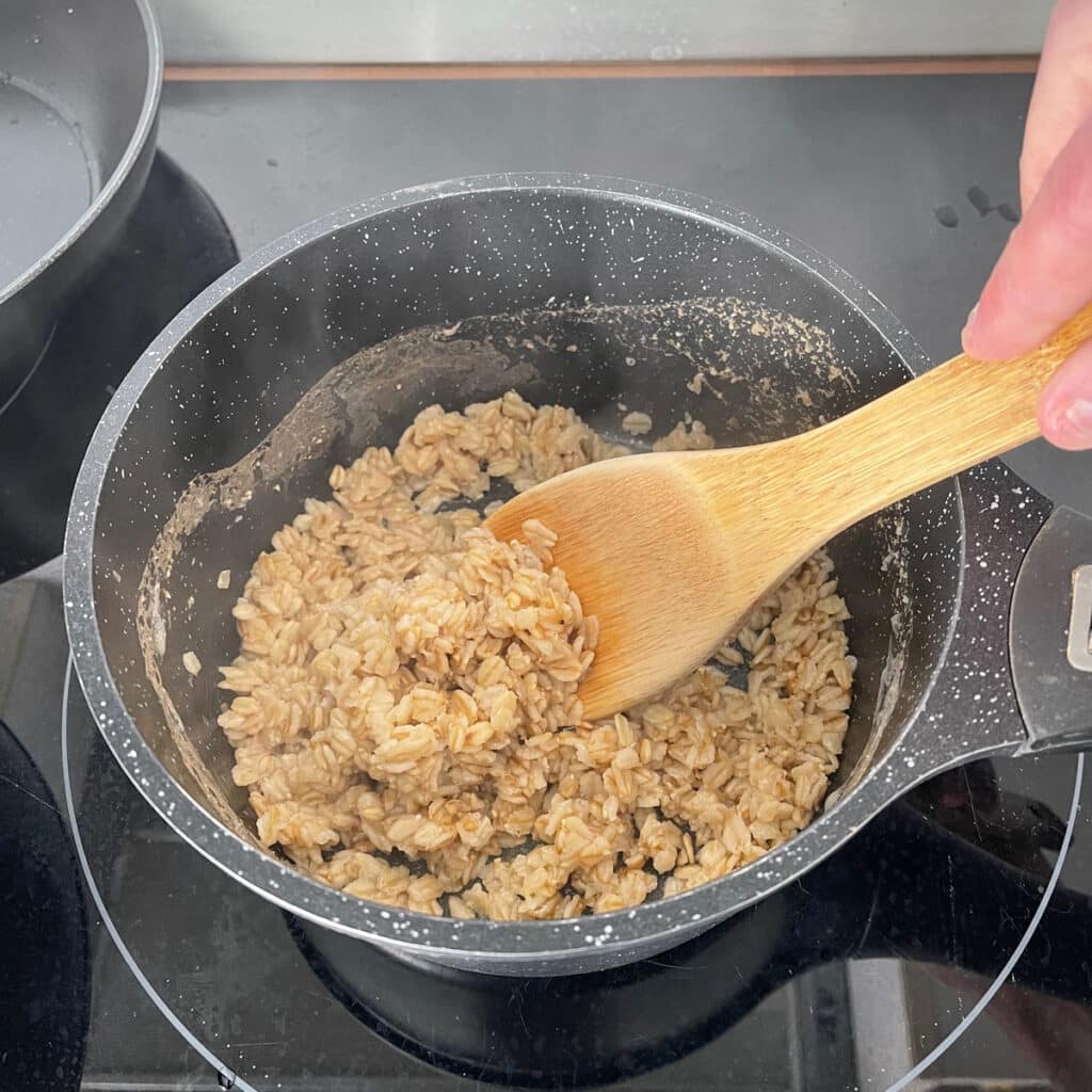 Stirring oats with water and seasonings or vegetable broth on a simmer