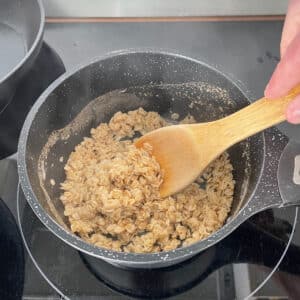 Stirring oats with water and seasonings or vegetable broth on a simmer
