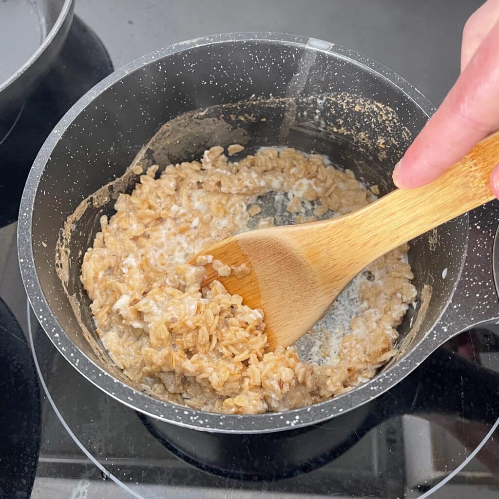 Stirring savory oatmeal with a wooden spoon, after adding egg whites