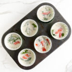 Blended egg whites and cottage cheese mixture divided in lined muffin tins, ready for baking in the oven