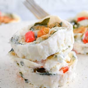Cheesy and tender Starbucks egg white bites made at home, after baking. 3 egg white bites are piled, showcasing flavorful spinach and roasted bell peppers on top