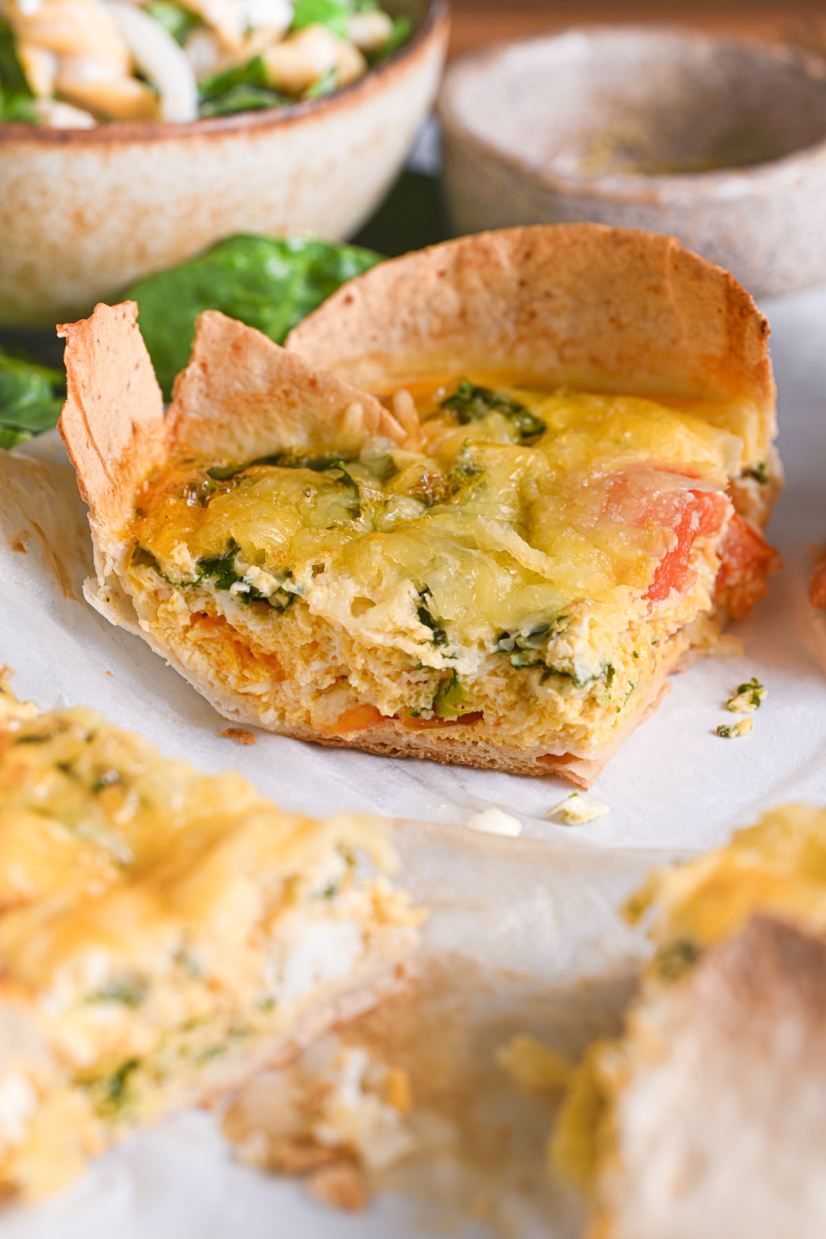 A slice of tortilla quiche with a golden cheesy topping. The image highlights its quiche-like egg filling, vibrant vegetables and a crispy crust.