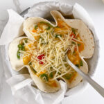 Shredded cheese sprinkled on top of the tortilla quiche, ready to bake in hot oven for a melty topping.