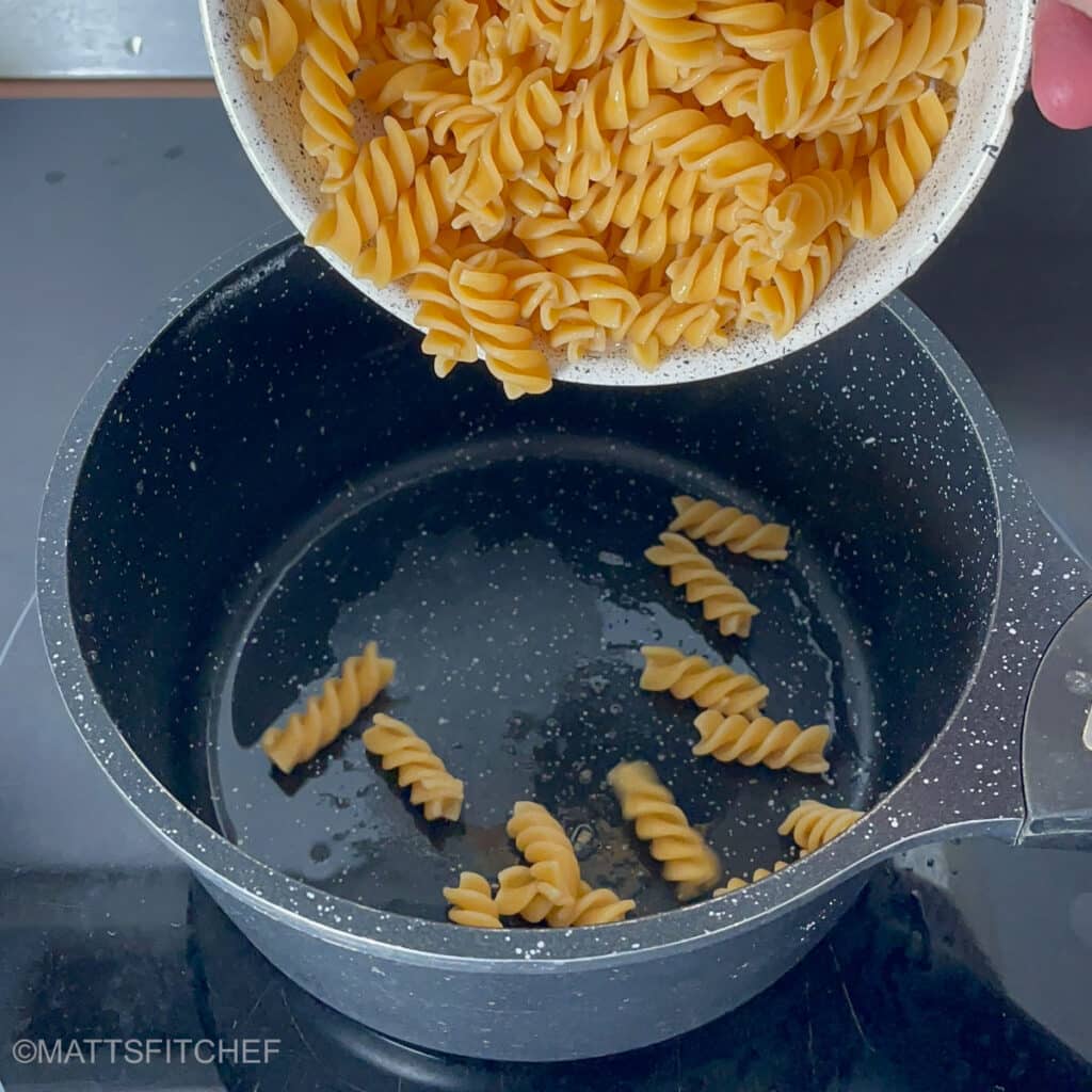 Adding cooked pasta sauce back to pot, before stirring with cottage cheese white sauce