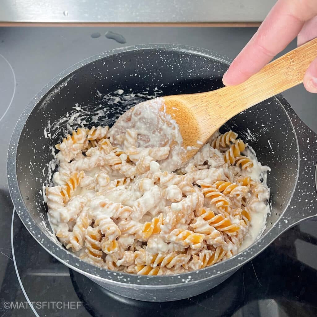 Stirring cottage cheese pasta sauce and pasta in a pot