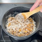 Stirring cottage cheese pasta sauce and pasta in a pot