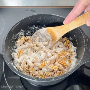Stirring cottage cheese pasta sauce and pasta in a pot