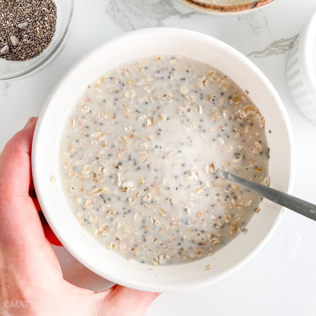 Oats mixed with cottage cheese and milk in a bowl, ready to soak overnight