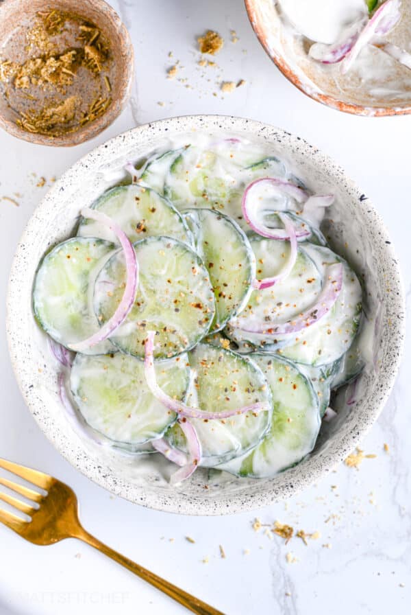 Creamy Greek yogurt cucumber salad with dill, seasonings and sliced red onion