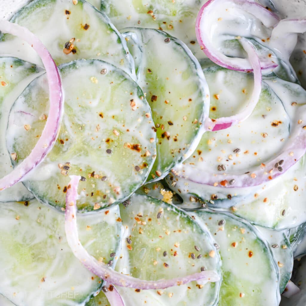 Close-up of creamy cucumber yogurt salad sprinkled with cracked black pepper