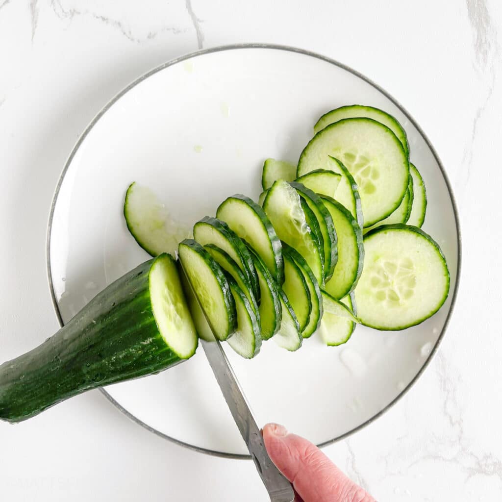 Slicing English cucumber thinly with a sharp knife