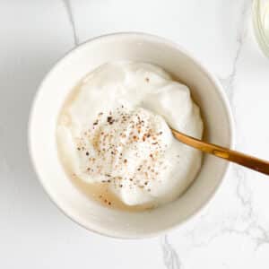 Greek yogurt mixed with lemon juice, dill, salt and pepper in a bowl.