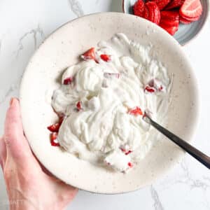 Stirring Greek yogurt and honey with diced strawberries