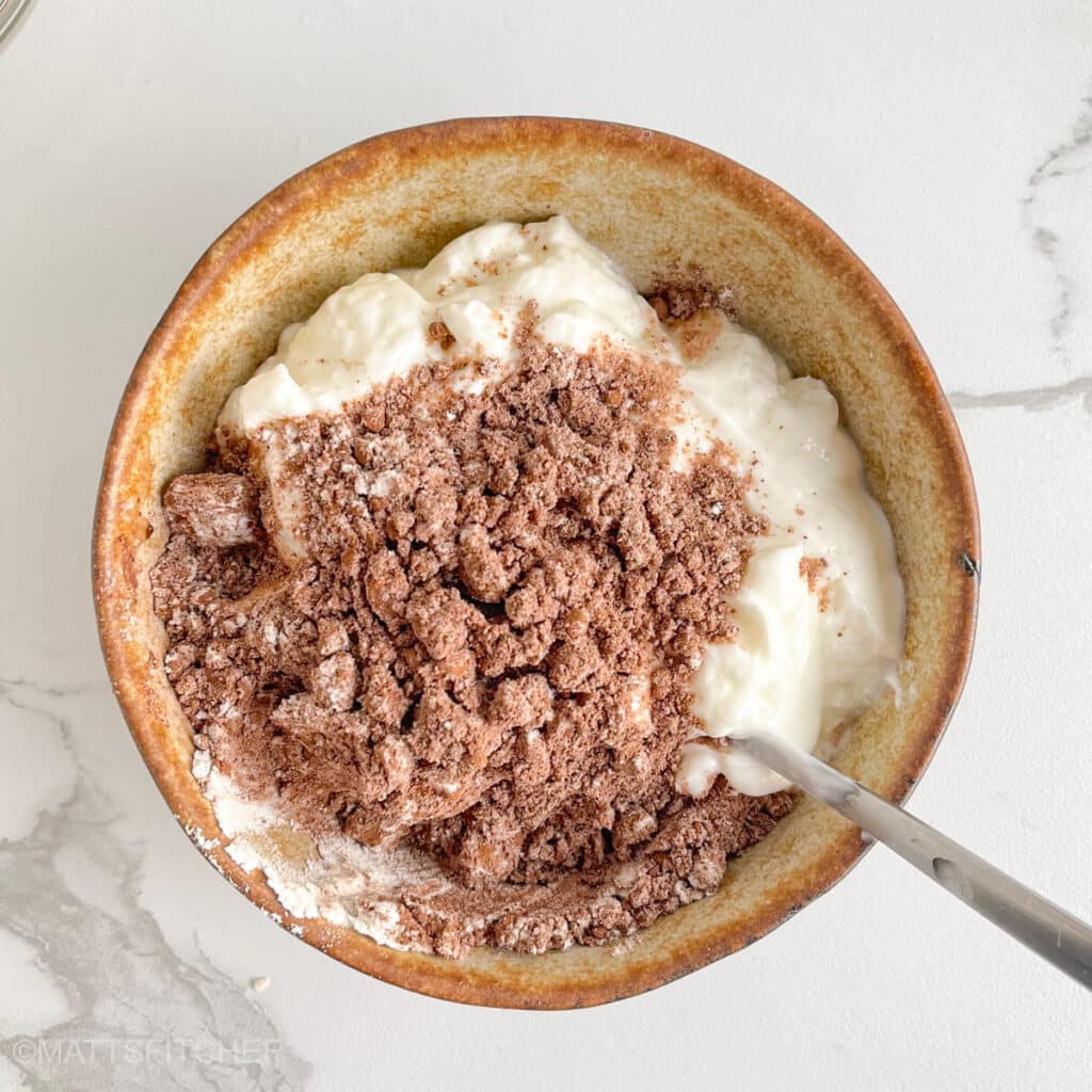 Adding protein powder in Greek yogurt, in small steps for easier mixing.