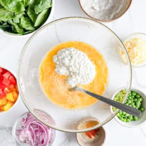 Cottage cheese added to beaten eggs, ready for mixing