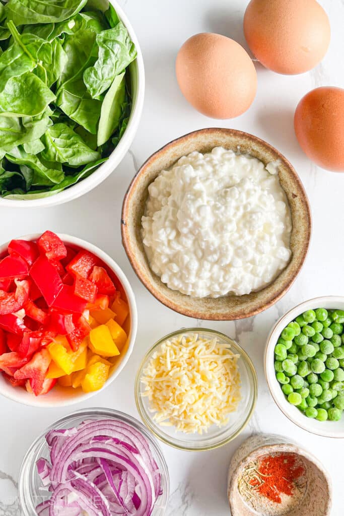 High protein breakfast casserole ingredients shown from top, highlighting whole eggs, creamy cottage cheese and vibrant vegetables