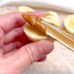 Spreading creamy peanut butter over banana slices
