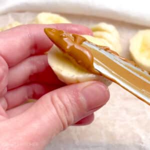 Spreading creamy peanut butter over banana slices